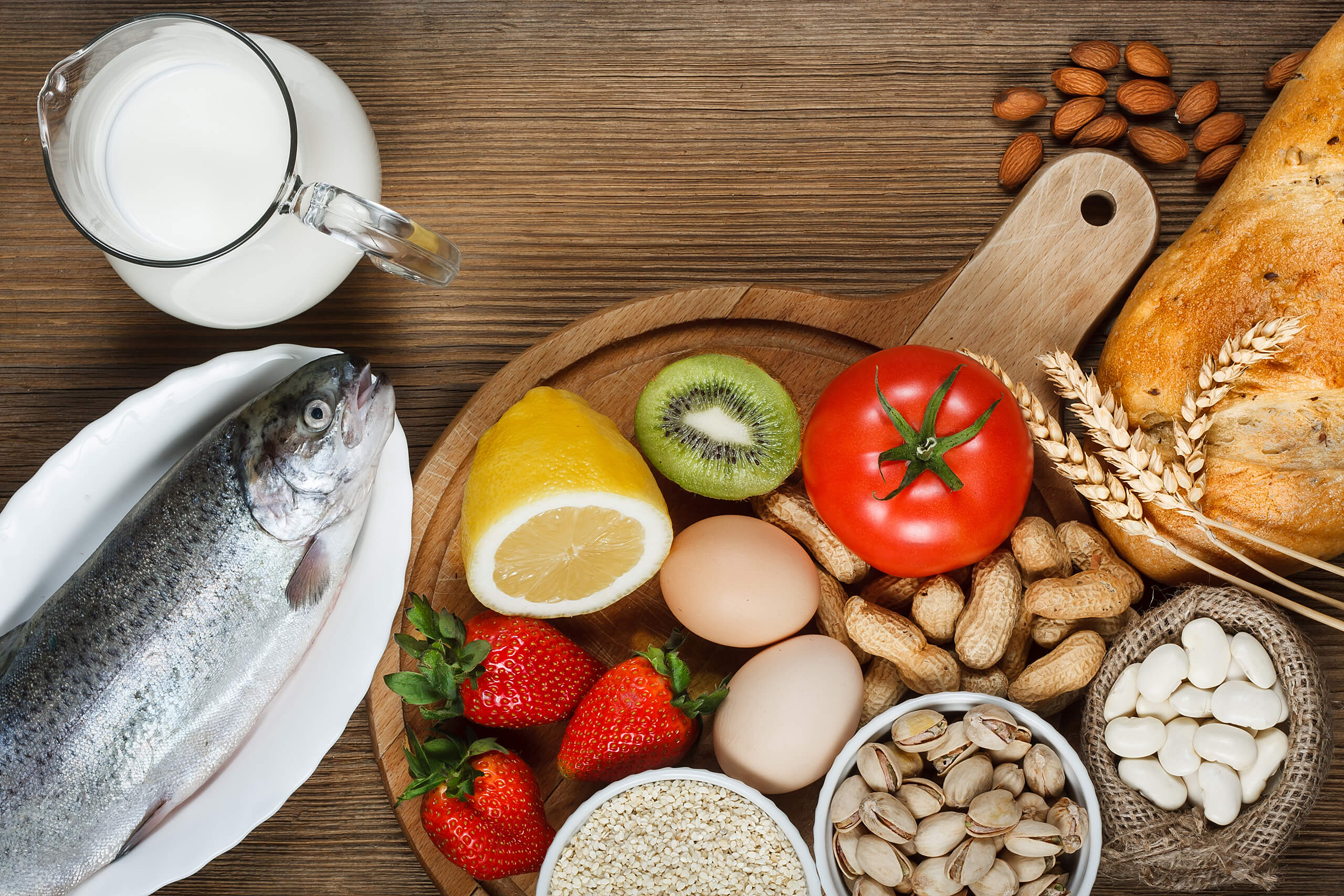 Obst, Gemüse, Fisch, Milch und Nüsse auf einem Holztisch